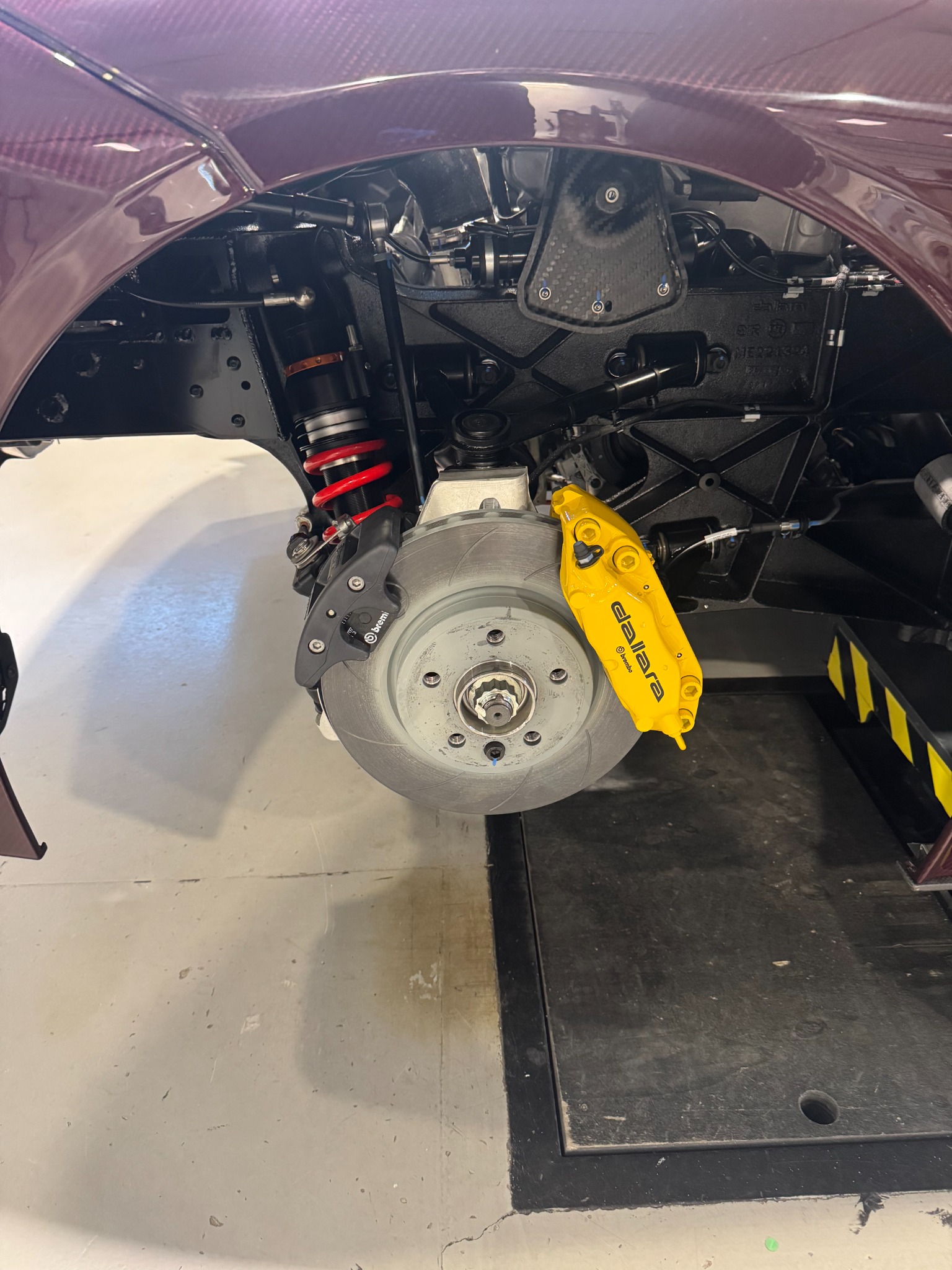 Close-up of Dallara Stradale suspension, brake rotor, caliper, and carbon-fiber structure